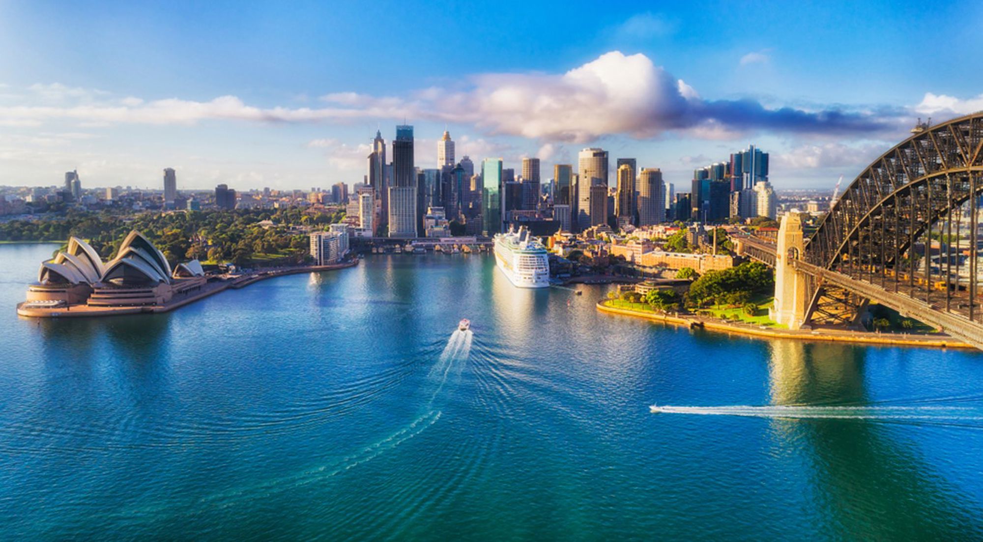 Sydney Harbour met het Opera House en de Harbour Bridge, met skyline en boten op het water.