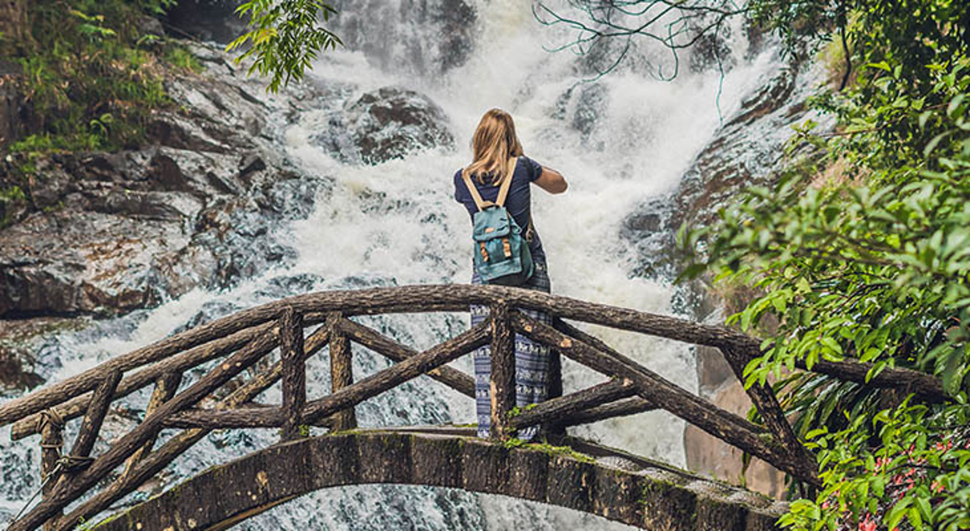 Da Lat Toerist met rugzak op brug bij waterval in Vietnam.