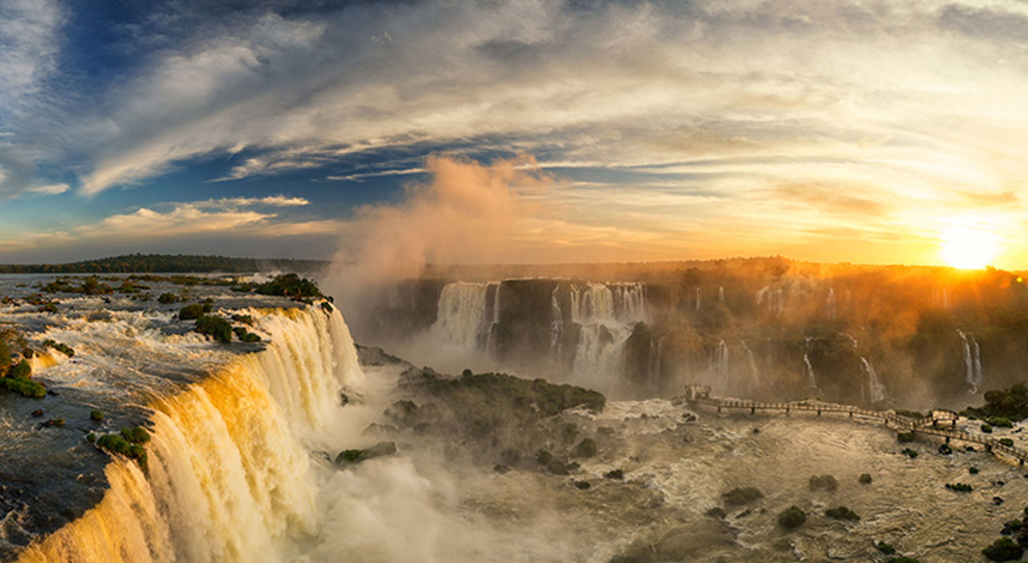 Iguazú-watervallen in Argentinië bij zonsondergang, met nevel boven de brede watervallen.