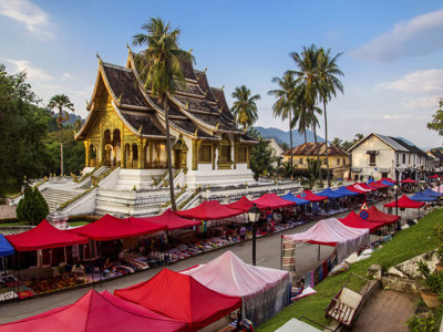 Gouden tempel in Luang Prabang met kleurrijke avondmarkt, tijdens familiereis Thailand, Laos en Cambodja.