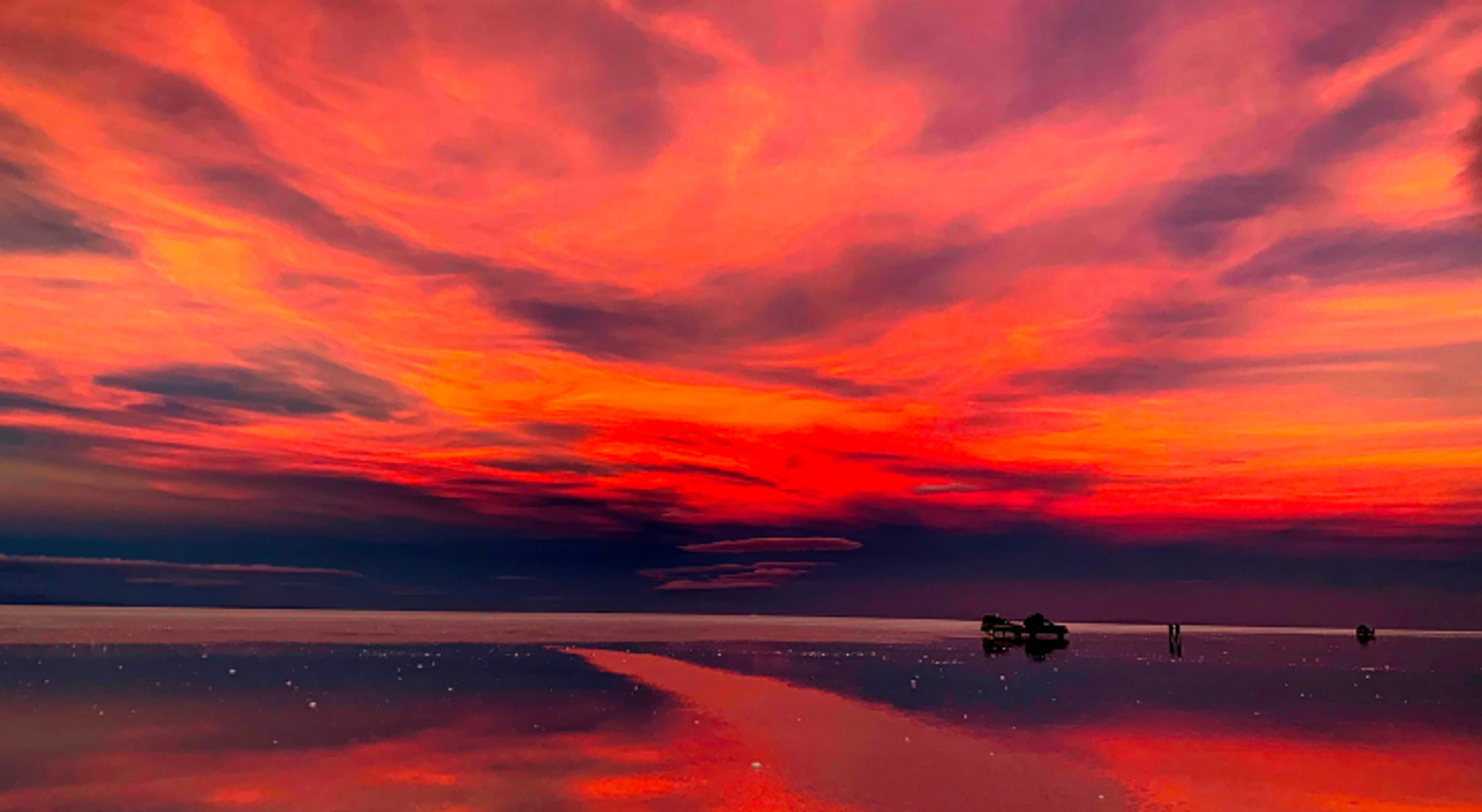 Salar de Uyuni Rode zonsondergang weerspiegeld in de zoutvlakte Salar de Uyuni in Bolivia.