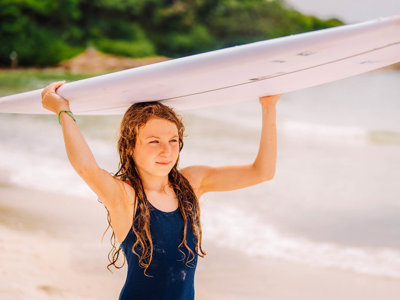 Meisje met surfboard op het strand tijdens familiereis Thailand.