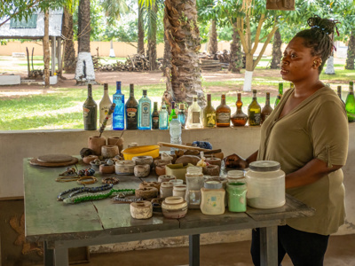 Marktkoopvrouw met kralen en potjes op tafel tijdens het Millet Festival in Ghana, Togo en Benin.